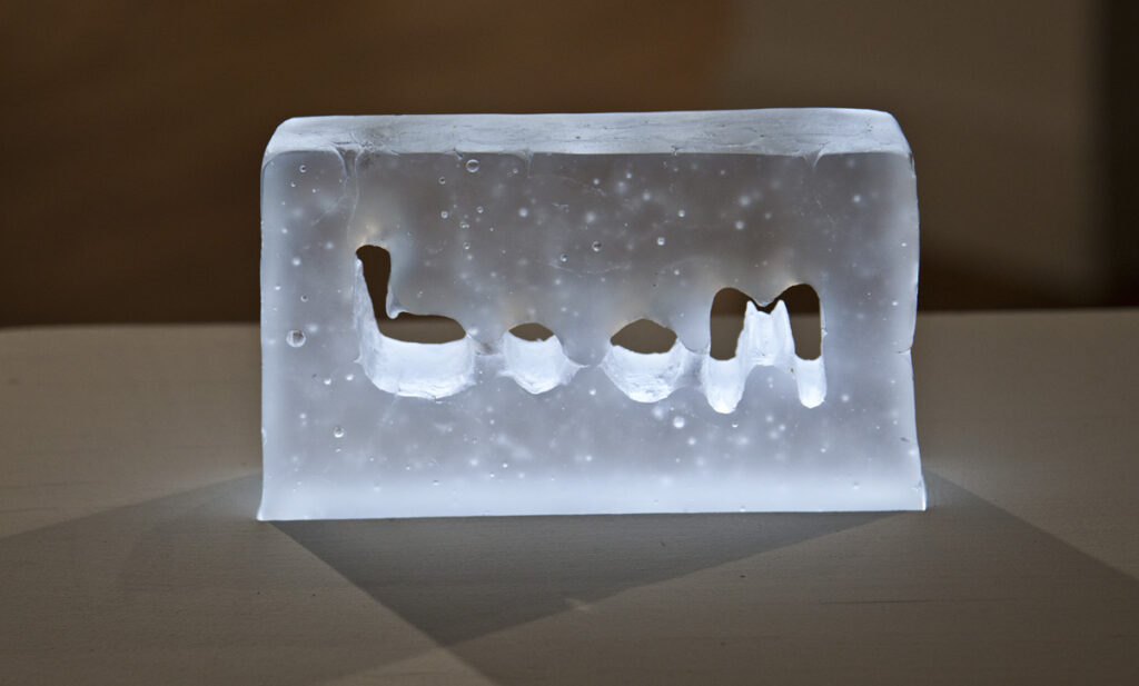 Close up Glass block with letters boom in middle lit from underneath glows blue white light