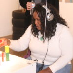 woman with headphones on building with blocks