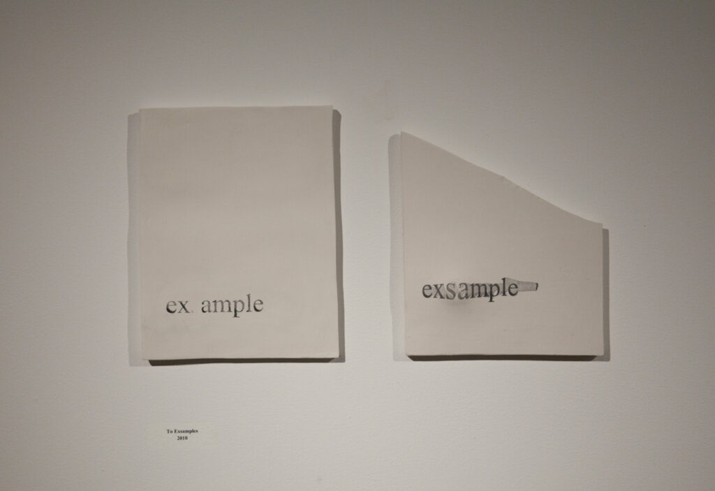 2 ceramic pages on wall one says E ample one says EXSAMPLE