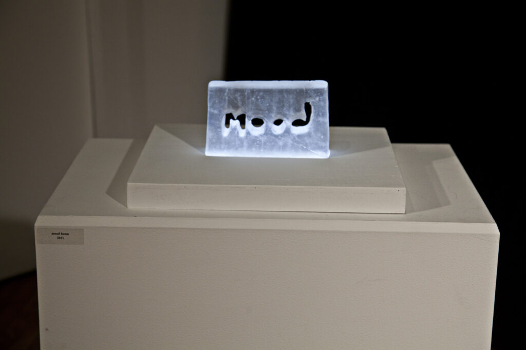 Glass block with letters mood in middle lit from underneath glows blue white light