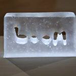 Close up Glass block with letters boom in middle lit from underneath glows blue white light