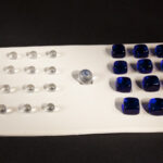 white game board similar to a chess set, set of pieces on left clear round glass, set on let blue glass squares, no move on the board, one piece blue and clear marble sits in the middle unable to move