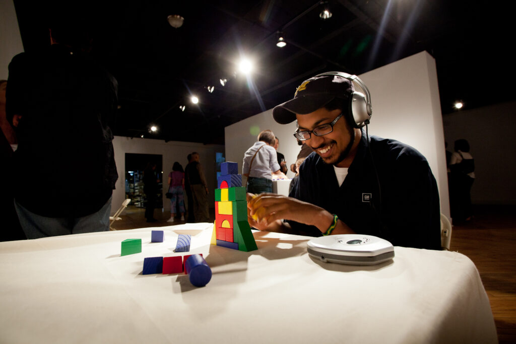 man sitting with headphones on building with multicolored blocks