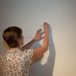 woman hanging a page of text on the wall